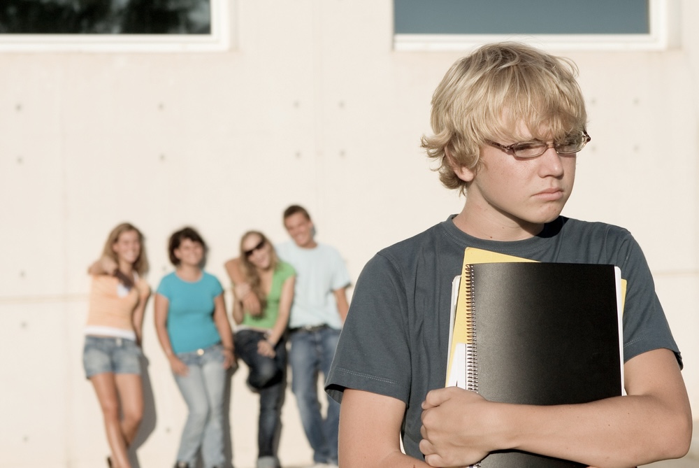 Nage boy isolates himself while a group of students are behind him