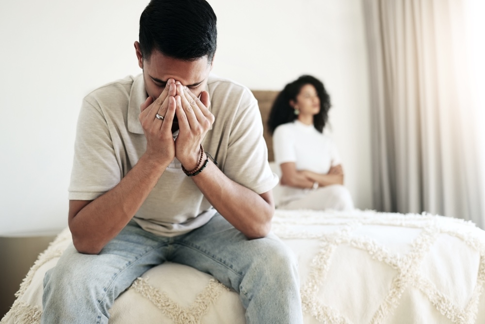 Man covers his face while sitting on the bed due to anxiety