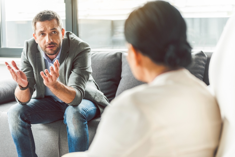 Man in a business suit tells a therapist why he’s embarrassed going to therapy